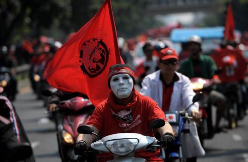 A Thai anti-government “Red Shirts” protester wearing a mask as he rides his motorcycle following a rally outside the criminal court to demand the release of their nine detained leaders in Bangkok on Feb. 13. (AFP-Yonhap News)