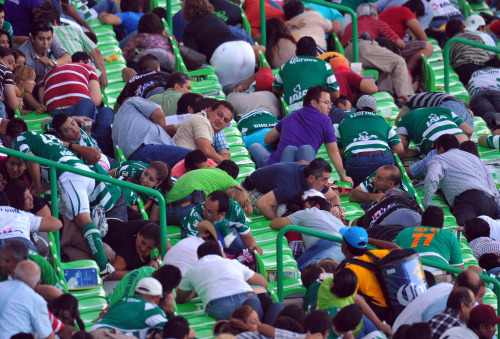 Fans protect themselves after hearing a shooting outside the Corona's stadium, in Torreon, northern Mexico, on Aug. 20, 2011.(Xinhua/AP)