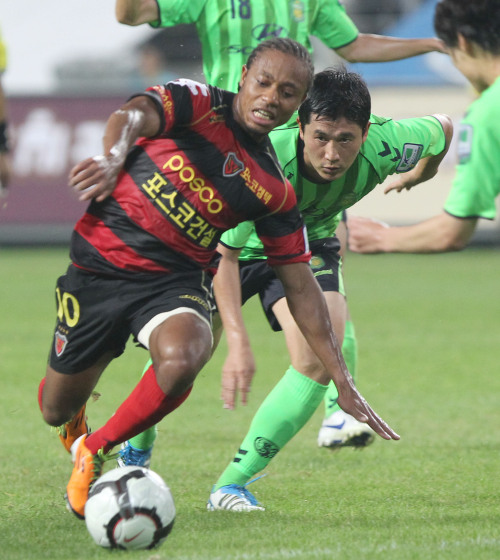 Pohang Steelers’ Derek Asamoah vies for the ball against Jeonbuk Hyundai’s defenders during their league game on Sunday. (Yonhap News)