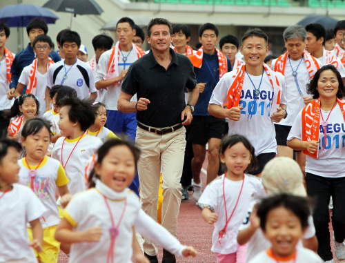 Sebastian Coe (center), chairman of London 2012 Olympic Committee and the vice president of the IAAF, runs with members of Daegu 2011 Sports Club on Tuesday at Daegu Citizen Stadium. (Yonhap News)