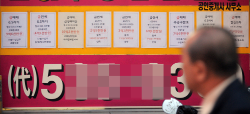 A passerby looks at the notice board of a real estate agency in southern Seoul on Tuesday. (Ahn Hoon/The Korea Herald)