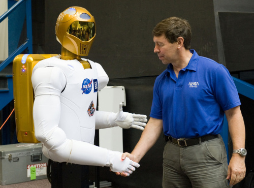 FILE - In this Aug. 4, 2010 file photo provided by NASA, astronaut Michael Barratt shakes hands with Robonaut 2, also known as R2, during a news conference in the Space Vehicle Mock-up Facility at NASA's Johnson Space Center in Houston.(AP)