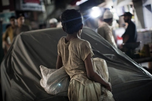 A Pakistani street child and scavenger leans on a car in downtown Karachi. (AFP)