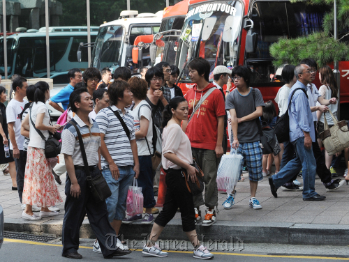 Tourists wait for their tour bus after shopping at Dongwha Duty Free Shop in Gwanghwamun on Thursday. Lee Sang-sub/The Korea Herald