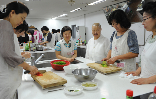 Buddhist nun Seonjae (third from right) coaches while her students cook temple food at the Korean Bhiksuni Association building in Suseo-dong, southern Seoul. (Lee Sang-sub/The Korea Herald)