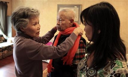 Shou-Mei Li (left) wraps a scarf around her husband Hsien-Wen Li, who is an Alzheimer’s patient, as their daughter Shirley Rexrode (right) looks on, at their home in San Francisco. (AP-Yonhap News)