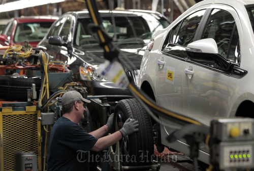 A worker puts a tire on a General Motors Co. 2012 Opel Ampera at Detroit-Hamtramck Assembly Plant in Michigan. (Bloomberg)