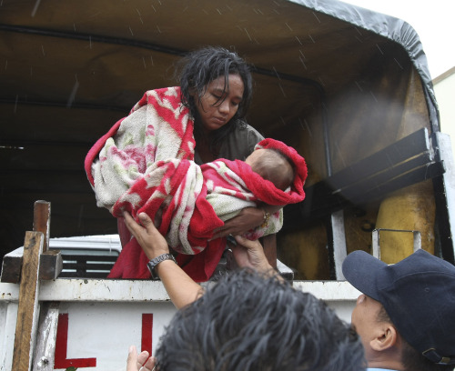 A woman arrives at an evacuation center with her baby after being rescued by police on Tuesday in Manila. (AP-Yonhap News)