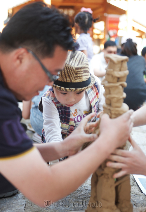 A boy focuses on building a clay tower at Yeoju Dojasesang.
