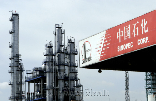 A Sinopec gas station stands in front of a Sinopec oil refinery in Pudong district, Shanghai. (Bloomberg)