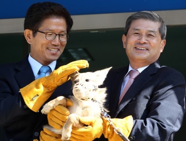 South Korean stem cell scientist Hwang Woo-suk (right) holds one of eight cloned coyotes with Gyeonggi Governor Kim Moon-soo at an animal shelter in Pyeongtaek, Gyeonggi Province, Monday. (Yonhap)