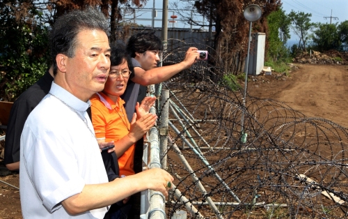 Lee Yong-hoon, chairman of Committee for Justice and Peace, listens to Hyun Ae-ja, former DP lawmaker, talk about the naval base at Gangjeong village near Seogwipo on Jeju last month. (Yonhap News)
