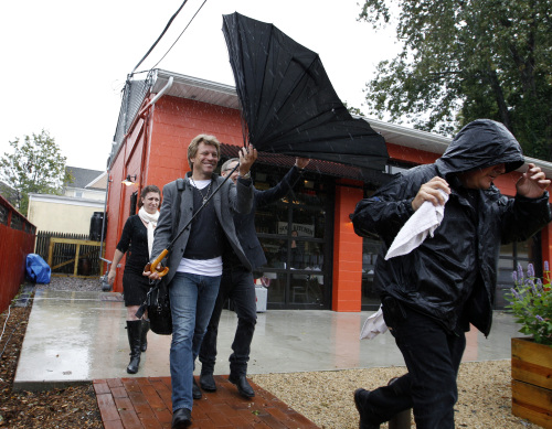 Rock star Jon Bon Jovi holds onto his umbrella in the wind and rain at the opening of his Soul Kitchen restaurant in Red Bank, N.J., Wednesday, Oct. 19, 2011. (AP)