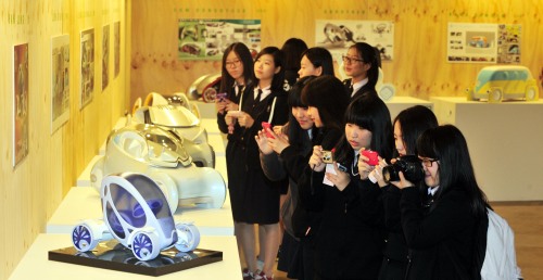 High school students take pictures of a wooden miniature of a concept car during their visit to Design Korea on Thursday. (Kim Myung-sub/The Korea Herald)