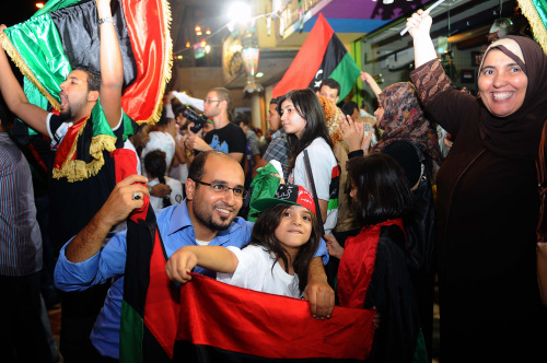 People wave pre-Gadhafi flags as they gather to celebrate the death of deposed Libyan dictator Moammar Gadhafi in Cairo, Egypt, Thursday. Moammar Gadhafi, Libya`s dictator for 42 years until he was ousted in an uprising-turned-civil war, was killed Thursday as revolutionary fighters overwhelmed his hometown of Sirte and captured the last major bastion of resistance two months after his regime fell. (AP-Yonhap News)