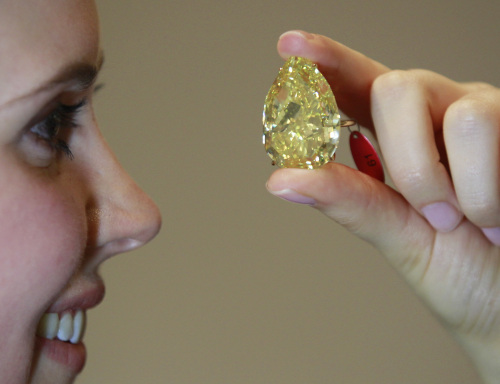 An auction house worker poses for the photographers holding a ring with the 'Sun Drop Diamond', 110.03 carat pear-shaped Fancy Vivid Yellow diamond, which according to the house is the most impressive and largest diamond ever to come to auction, in London, Monday, Oct. 24, 2011. Sotheby's will hold its Autumn Sale of Magnificent Jewels on Nov. 15, 2011 and the diamond is estimated to fetch between11-15 million US dollars. (AP-Yonhap News)