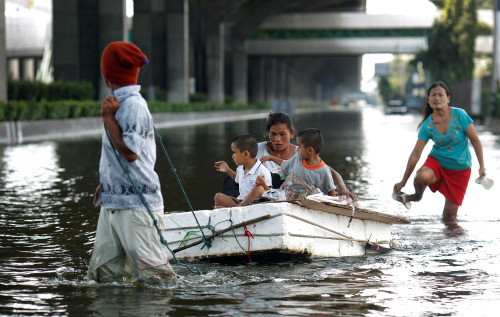 A family wades down a flooded street in Bangkok, Thailand, on Wednesday, Oct. 26, 2011. Thai Prime Minister Yingluck Shinawatra said a 