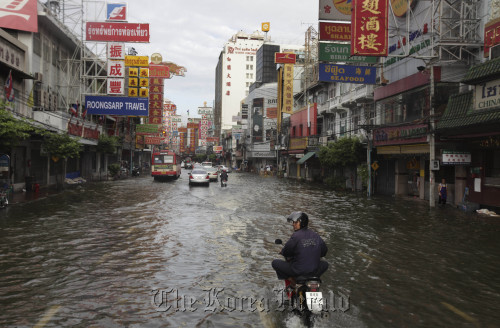 Local residents wade through floodwaters in Bangkok on Sunday. (AP)