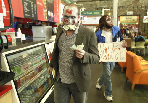 Occupy Wall Street protesters, made up to look like zombies for Halloween, pretend to eat money as they walk through a dining area at the River Market district in Little Rock, Ark., Monday, Oct.31, 2011. (AP-Yonhap News)