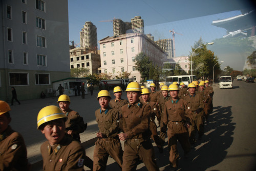 In this photo taken through the window of a vehicle on Oct. 26, North Korean construction workers march on the road in Pyongyang in North Korea. (AP-Yonhap News)