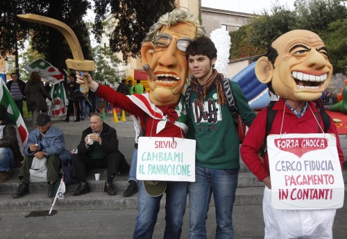 Demonstrators wear masks mocking Italian Premier Silvio Berlusconi (right) and Reform Minister Umberto Bossi carrying placards reading: 