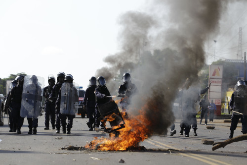 Liberian police advance past a burning barricade in Monrovia, Liberia on Monday. (AP-Yonhap News)