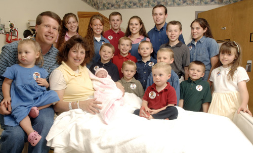 Michelle Duggar (left) is surrounded by her children and husband Jim Bob (second from left) after the birth of her 17th child in Rogers, Ark. (AP)
