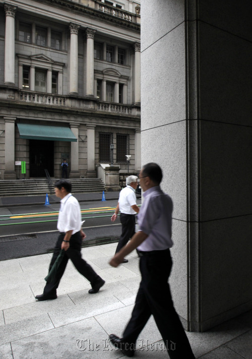 Pedestrians walk past the Bank of Japan headquarters in Tokyo. (Bloomberg)