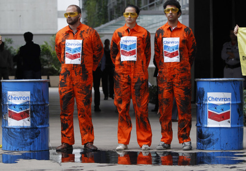 Greenpeace activists protest using fake oil to protest an oil spill in an offshore field operated by Chevron Corp, outside Chevron’s offices in Rio de Janeiro, Brazil, Friday. (AP-Yonhap News)