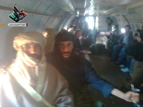 In this image provided by the Zintan Media Center, Seif al-Islam Gadhafi (left) is guarded by a Libyan fighter as he is transported to Zintan, Libya, by a transport aircraft following his capture near the Niger border early Saturday. (AP-Yonhap News)