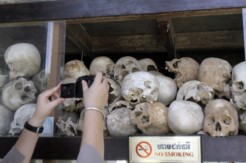 A tourist takes pictures of human skulls of Cambodian Khmer Rouge victims at Choeung Ek stupa, better known 