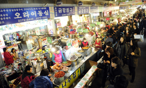 As dusk gathers, people gather at Gwangjang Market’s famed food bazaar for a tasty bite or two. (Park Hae-mook/The Korea Herald)