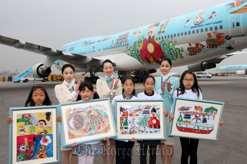 Winners of a Korean Air drawing contest pose with flight attendants in front of the aircraft wrapped with one of their paintings at the Gimpo Airport on Saturday. ( Korean Air)