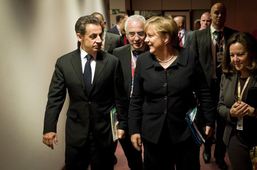 German Chancellor Angela Merkel (right) and French President Nicolas Sarkozy talk on their way to a working dinner during the EU summit in Brussels on Thursday. (AP-Yonhap News)