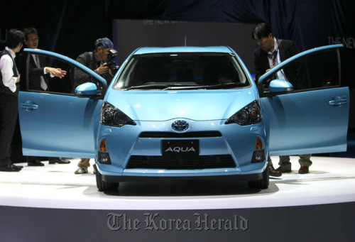 Visitors look at a Toyota Motor Corp. Aqua hybrid vehicle at the Tokyo Motor Show 2011 in Tokyo. Toyota delayed the new projections by a month because of the floods. (Bloomberg)