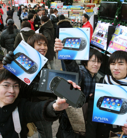 People show off their newly purchased PlayStation Vita portable consoles in Tokyo on Saturday. (AP-Yonhap News)