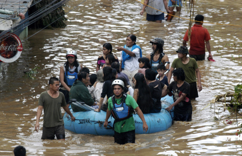 Volunteers use rubber a boat to ferry residents to safer grounds following a flash flood that inundated Cagayan de Oro city, Philippines, Saturday. A tropical storm triggered flash floods in the southern Philippines, killing scores of people and missing more. Mayor Lawrence Cruz of nearby Iligan said the coast guard and other rescuers were scouring the waters off his coastal city for survivors or bodies that may have been swept to the sea by a swollen river. (AP-Yonhap News)