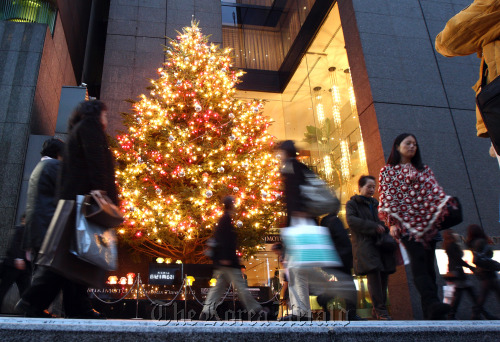 Shoppers walk past an illuminated Christmas tree in Tokyo. (Bloomberg)