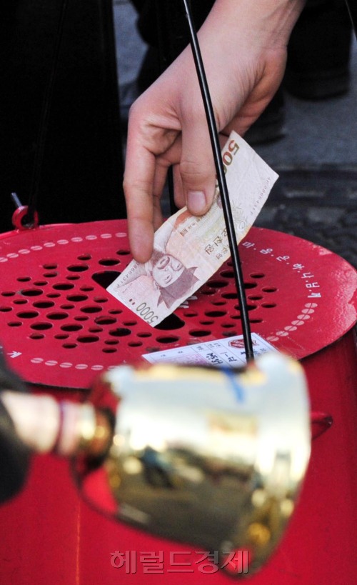 A Seoulite drops a 5,000 won note into the Salvation Army charity pot set up in Myeong-dong, Seoul. (Kim Myung-sub/The Korea Herald)