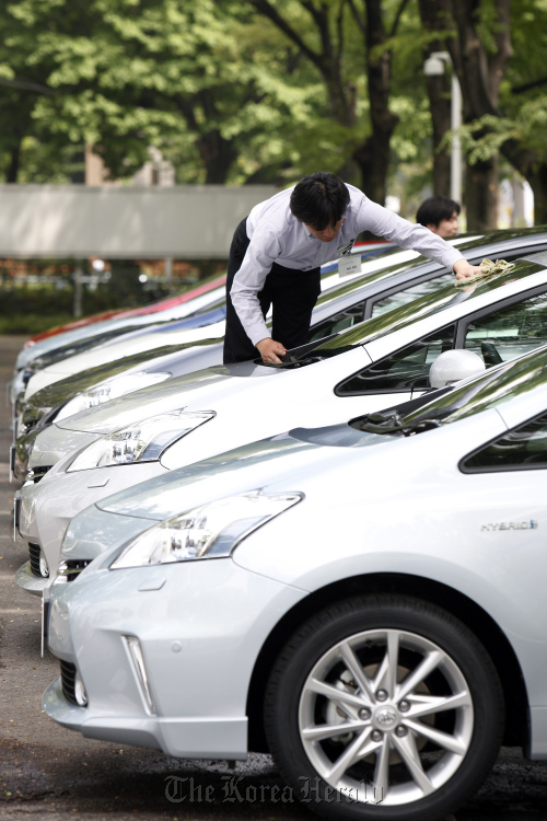 A worker cleans Toyota Motor Corp.’s new Prius Alpha hybrid vehicles during a media preview in Tokyo. (Bloomberg)