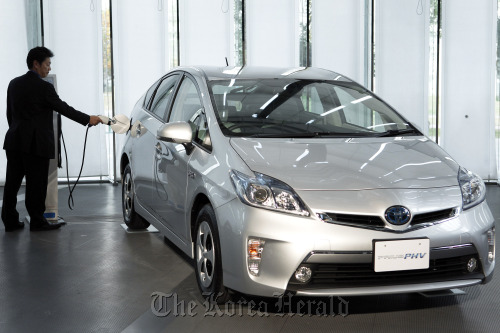 An employee demonstrates the charging of Toyota Motor Corp.’s Prius plug-in hybrid vehicle during the unveiling in Tokyo. (Bloomberg)