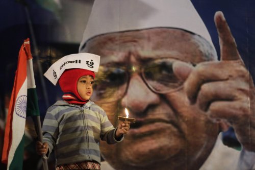 A young supporter of Indian anti-corruption activist Anna Hazare, depicted in the background, wears a cap that reads “I am Anna” as he hold the Indian flag during a protest against corruption in Ahmadabad, India, Tuesday. (AP-Yonhap News)