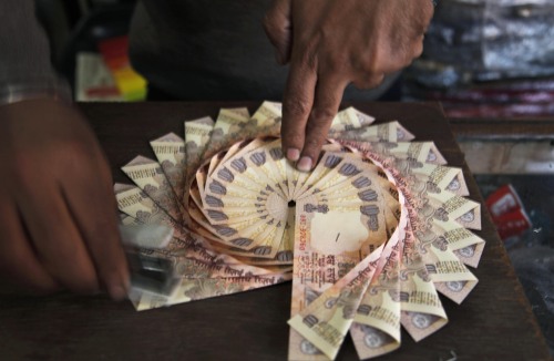 A vendor makes a garland with Indian 10 rupee currency for sale in Jammu, India. (AP-Yonhap News)