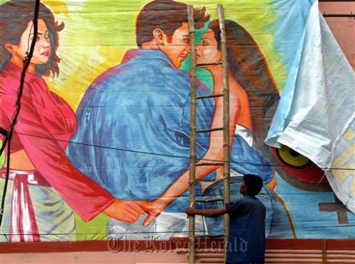 A movie theater worker removes a poster of the Bollywood film “Girlfriend,” a film about a lesbian couple, after Hindu hard-liners demanded a ban on the film, in Allahabad, India in 2004. (AP-Yonhap News)