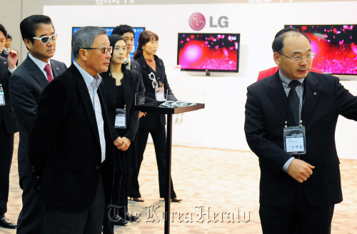 LG Group chairman Koo Bon-moo (second from left) is briefed by a company executive on the electronic firm’s 55-inch OLED TV to be released soon on Friday. (Yonhap News)