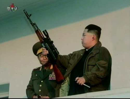 North Korean leader Kim Jong-un (right) is seen holding up a rifle in a still from a film about his activities aired on Korean Central News Agency on Sunday. (Yonhap News)