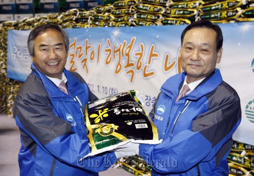 Woori Financial Group chairman Lee Pal-seung (right) poses after donating 3,500 bags of rice to the Korea Association of Social Welfare Centers on Tuesday as part of the group’s social activities ahead of the Lunar New Year holiday. (Woori Financial)