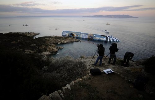 Cameramen film the stricken cruise liner Costa Concordia off the Isola del Giglio.(AFP)