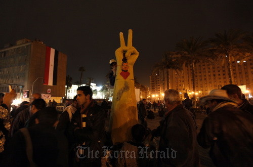 An Egyptian protester paints on a sculpture of a hand making a victory sign at Tahrir Square in Cairo, Tuesday. (AP-Yonhap News)