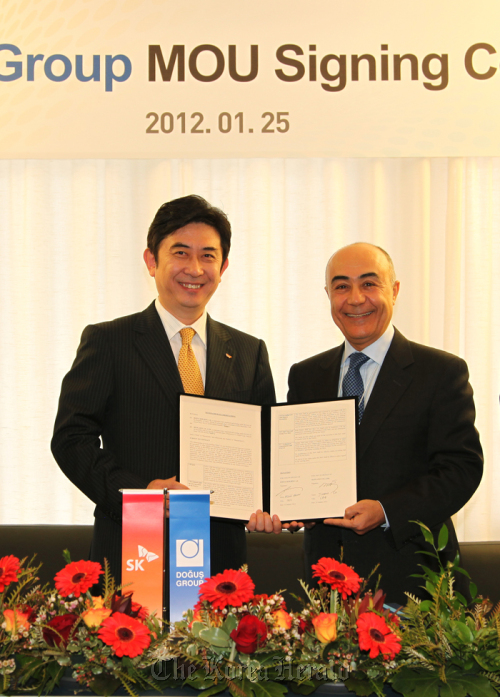 SK Planet CEO Seo Jin-woo (left) and Dogus Grubu CEO Husnu Akhan stand with a memorandum of understanding at Holland House, a mountain resort in Davos, Switzerland, Wednesday. (SK Planet)